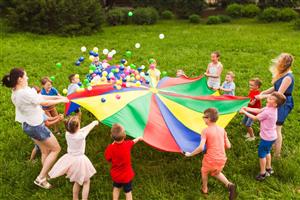 Camp counselors and kids bouncing balls on a colorful parachute Camp counselors and kids bouncing balls on a colorful parachute