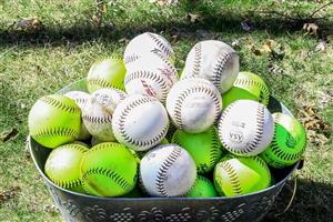 Metal bucket filled with white and neon yellow softballs.